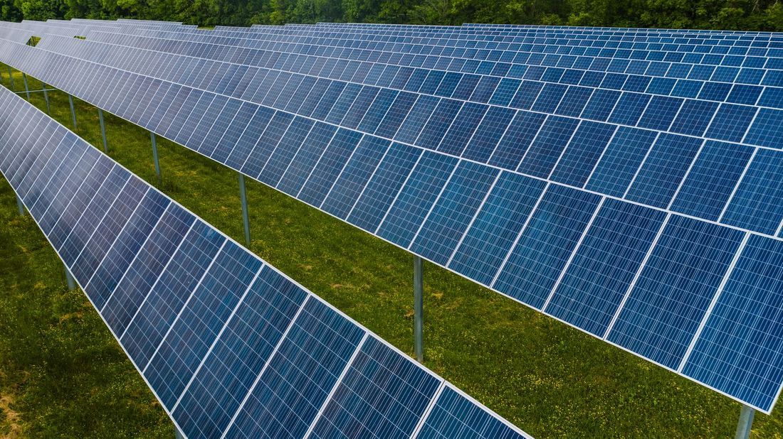 Long rows of ground-mounted solar panels on grass