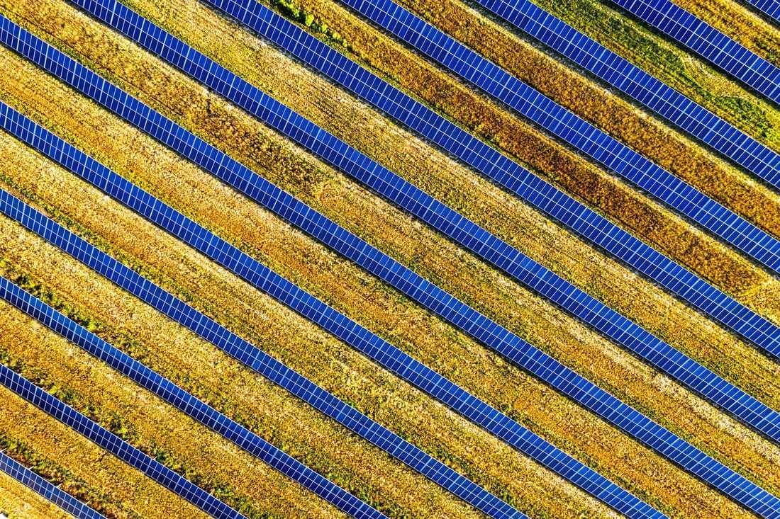 Aerial view of diagonal rows of solar panels in a field